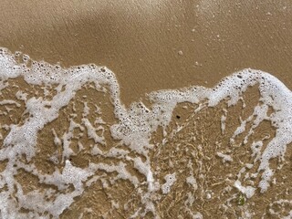 Fototapeta na wymiar a foamy wave on the sand of the north sea beach