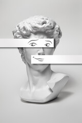 Replica of the head of an antique statue of David with a taped eyes and mouth on white background. Painted smile and eyes on white blank.