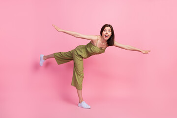 Full length photo of positive impressed pretty lady open arm stand one leg fly empty space isolated on pink color background