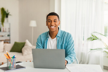 Fototapeta premium Smiling young african american businessman or manager uses computer for study, work