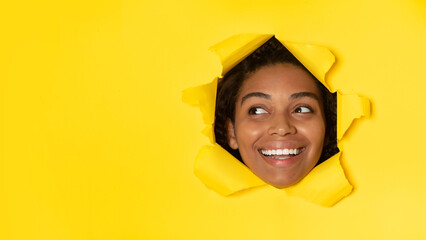 Black Woman Looking Aside Through Hole In Paper, Yellow Background