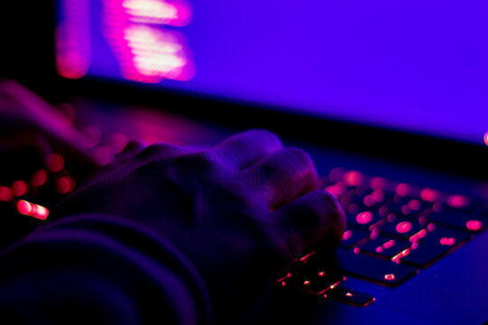 Female developer working in the dark. Focused on hands.