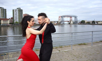 Young, beautiful and professional couple dancing tango on the quay of the river