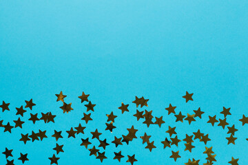 Golden confetti stars on color background, top view