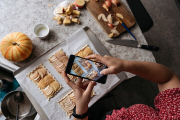 Female hands taking pictures of apple tart with mobile phone