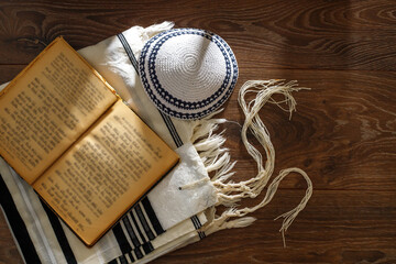 Jewish traditional prayer supplies. Talite, kippah, torah on a wooden table. Shabbatta, Bar...
