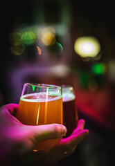 Two friends hands toasting with glasses of craft beer at the pub or bar. taproom