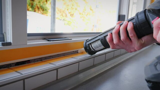 Master with spray gun fills up gap between window with construction sealant
