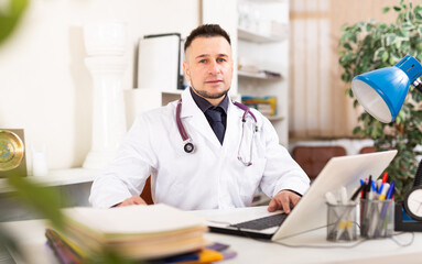 Portrait of young focused man doctor at workplace in clinic office