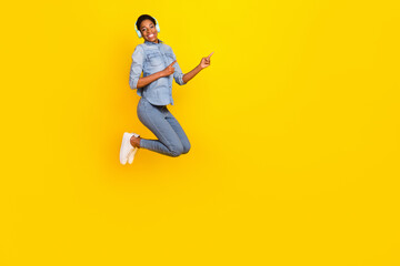 Fototapeta na wymiar Full length photo of active person wireless earphones direct fingers empty space isolated on yellow color background