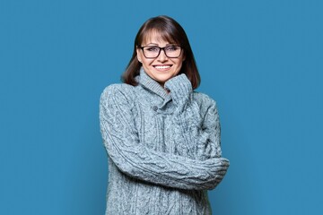 Portrait of smiling middle aged female looking at camera on blue background