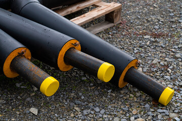 Black metal pipes in isolation lie on a construction site.