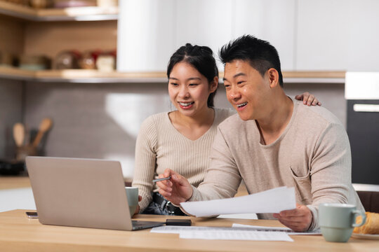 Positive asian couple paying for goods and services on Internet - Powered by Adobe