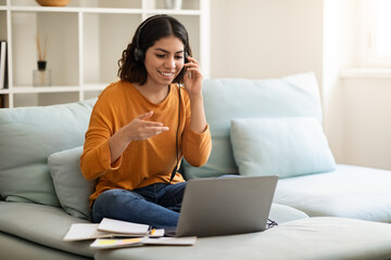 Online Tutoring. Smiling Arab Woman In Headset Making Teleconference With Laptop