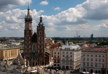 Fototapeta na wymiar Krakow, Poland, July the 15th 2022. The crowded central market square of Krakow with St Mary's Basilica by the side of it.