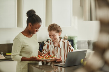 Portrait of two young women sharing meal in cozy home kitchen, copy space