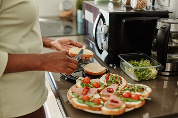 Close up of black young woman making sandwiches while cooking dinner in kitchen, copy space