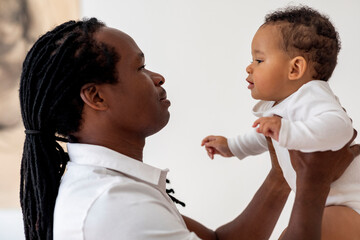 Father's Care. Young Black Dad Bonding With Cute Infant Baby At Home