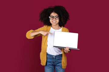 Cute african american schooler showing computer with blank screen, mockup