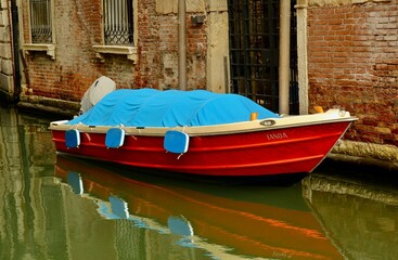 Fototapeta na wymiar Red boat on the Venetian canal 