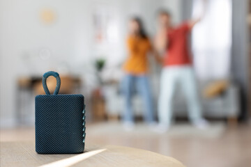 Selective focus on brand new portable speaker over singing couple