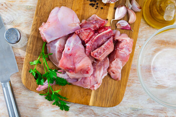 Raw sliced rabbit lying on wooden cutting board with seasonings. Dietary cooking ingredient ..