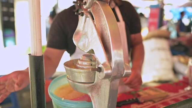 Elaboraci&oacute;n de jugo de naranja en un puesto de alimentos en una de las calles en Am&eacute;rica Latina.