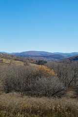 Landscape scene with rolling mountains and late fall colors. Vertical view, blue sky, copy space, background.