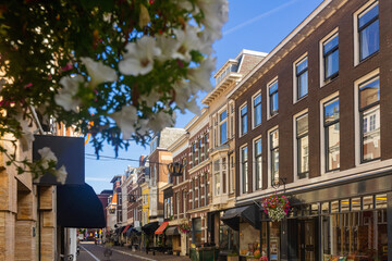 View of historical district of Old Town The Hague overlooking narrow picturesque street with old buildings, shops and open air restaurants on sunny summer day, Netherlands.