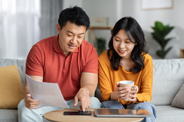 Happy asian family calculating monthly spending at home