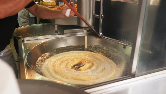 Street food Porras type churros being cooked in oil. Traditional Spanish food.