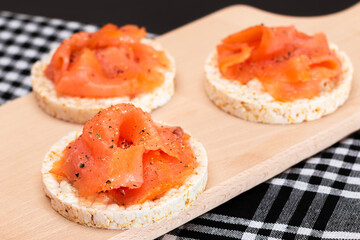 Tasty Rice Cake Sandwiches with Fresh Salmon Slices on Wooden Cutting Board. Easy Breakfast and Diet Food. Crispbread with Red Fish. Healthy Dietary Snack