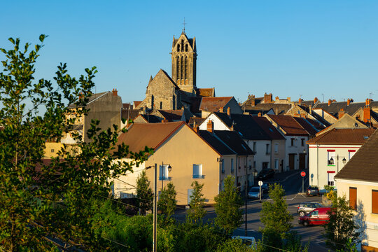 Townscape of Dormans, France. View of residential buildings along streets and catholic church in background.