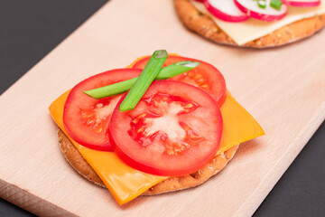 Different Cracker Sandwiches with Tomato, Cucumber, Radish and Cheese on Cutting Board. Easy Breakfast. Diet Food. Quick and Healthy Sandwiches. Crispbread with Tasty Filling. Healthy Dietary Snack
