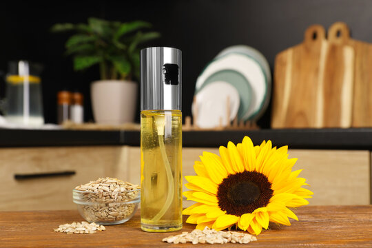 Sunflower, seeds and spray bottle with cooking oil on wooden table in kitchen