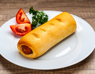 Baked Sausage Roll with tomato and parsley on white plate