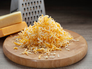 Shredded mozzarella and red cheddar cheese on wooden cutting board