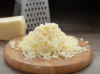 Foto op Plexiglas Shredded mozzarella cheese on wooden cutting board and shredder © Robert Stedman