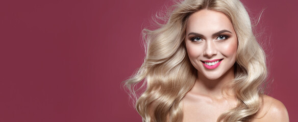 Fototapeta premium Fashion beauty portrait of a blonde woman with blue eyes and Healthy Long Shiny Wavy hairtyle. Volume shampoo. Blond Curly permed Hair and bright makeup. Beauty salon and haircare concept.