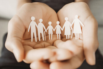 Hands holding multi generational family paper, family wellness, health insurance concept