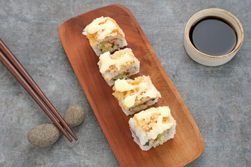 Sushi Rolls Mayo with crab stick, ebi, cucumber served on wooden plate
