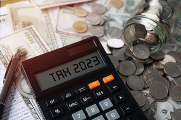 Tax 2023. Word Tax 2023 on calculator. Business and tax concept .Calculator, currency, dollar bills close up. Income Statement. paying the tax rate. Taxation, taxes burden. Business concept.