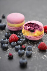 Delicious macaroons and berries on a black tray.