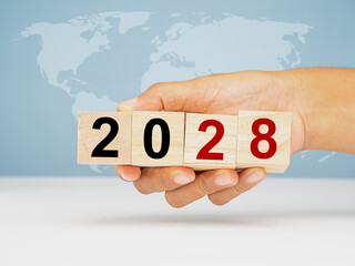 Countdown and Business planning in 2028. Hand holding of wooden cubes with the letters 2028 over...