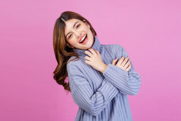Portrait of Smiling young woman sweet winsome lovely attractive charming cheerful cheery lady hugging herself isolated over pink background