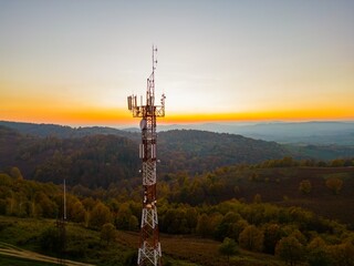 Aerial view of telecommunication tower situated on a hill top, with many cellular antennas which...