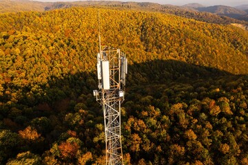 Aerial view of telecommunication tower situated on a hill top, with many cellular antennas which transmits 3G, 4G and 5G signal to phones and other terminals - Powered by Adobe