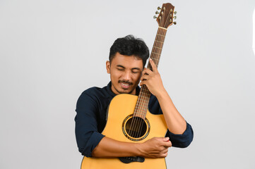 Obraz premium Portrait of Happy young Asian man hugging an acoustic guitar isolated on white background
