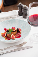 Rose roasted duck with fig and drops of red wine sauce on a white plate