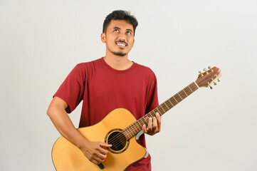 Portrait of Young Asian man in red t-shirt playing an acoustic guitar isolated on white background